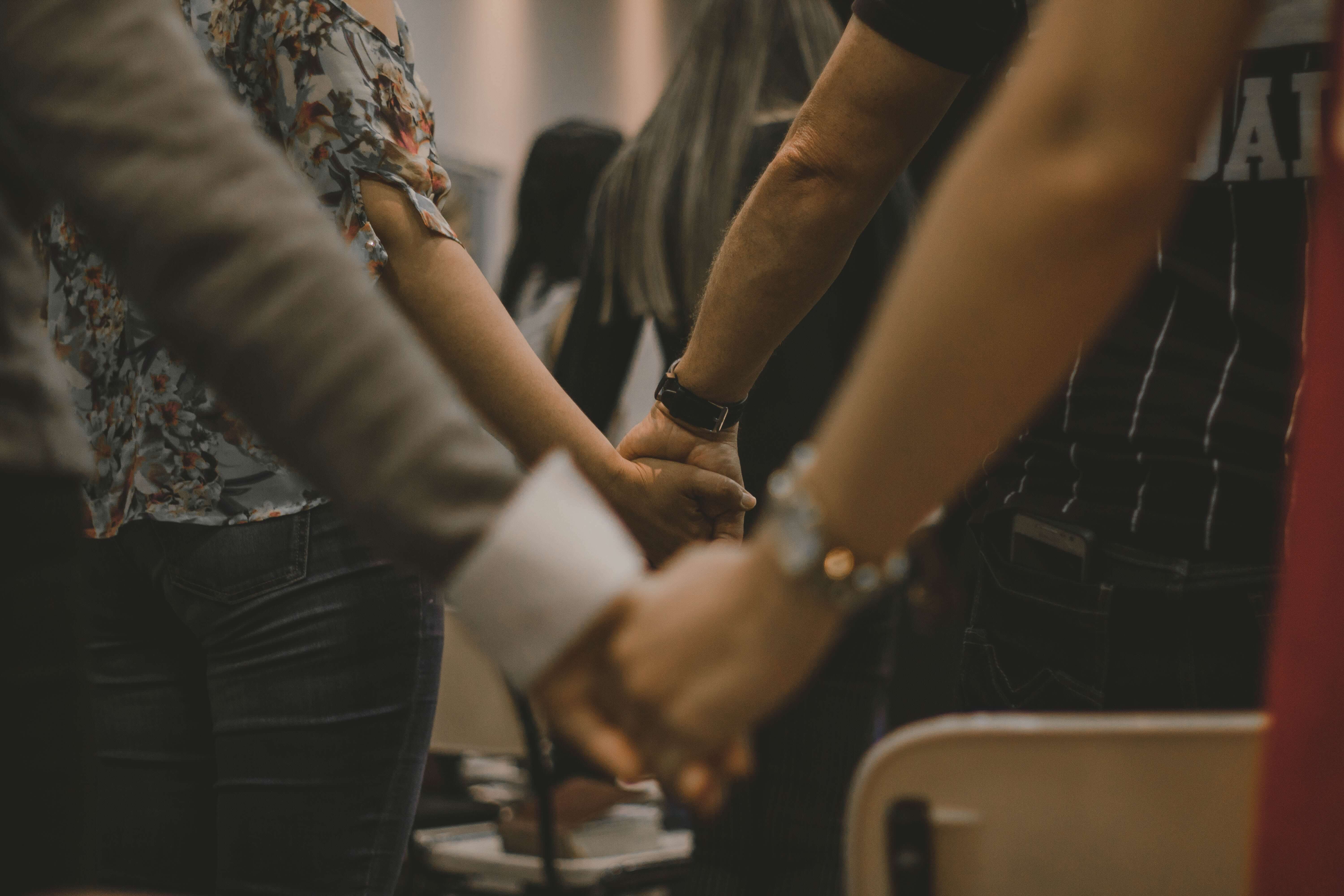 a group of people holding hands praying